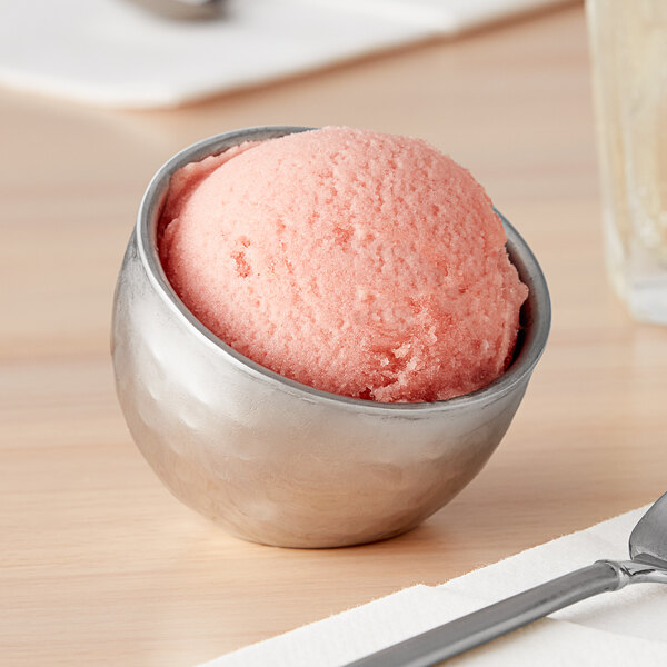 An American Metalcraft stainless steel bowl of pink ice cream sits on a table.