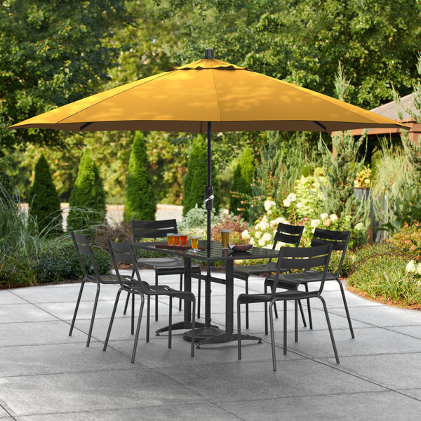 A yellow Lancaster Table & Seating umbrella on an outdoor patio table.