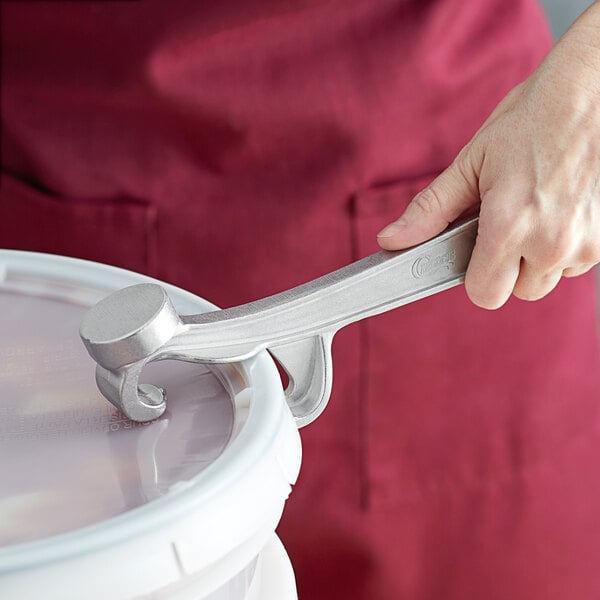 A hand using a Choice aluminum pail opener on a bucket.