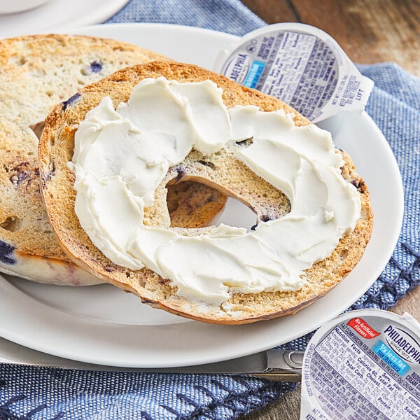 A bagel with Philadelphia Reduced Fat Cream Cheese on a plate.