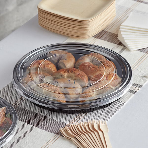A Choice plastic catering tray with food in it and wooden forks on a table.
