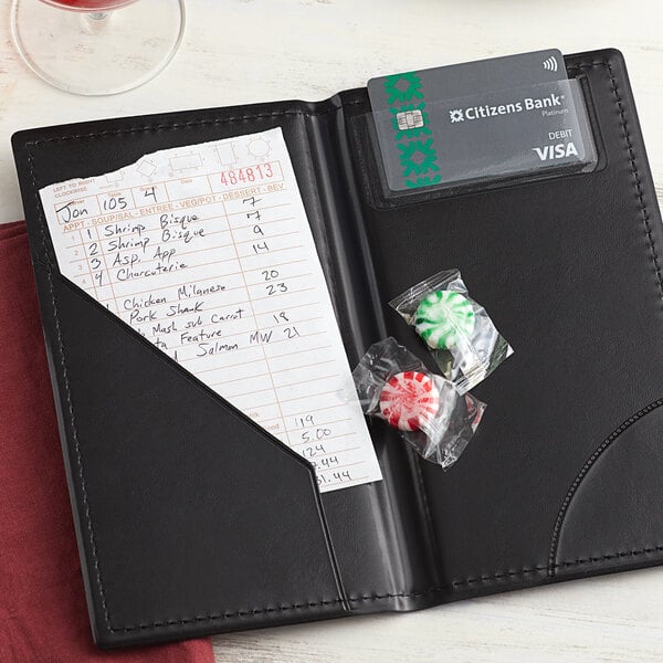A black leather Choice guest check presenter with a receipt and candy inside.