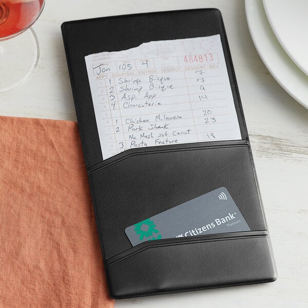 A black leather Choice guest check presenter on a table with a receipt and card.