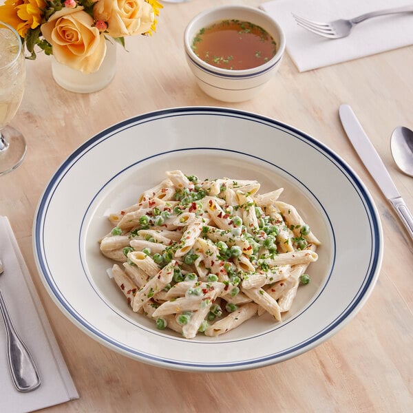 An Acopa ivory stoneware bowl with pasta, sauce, and peas.
