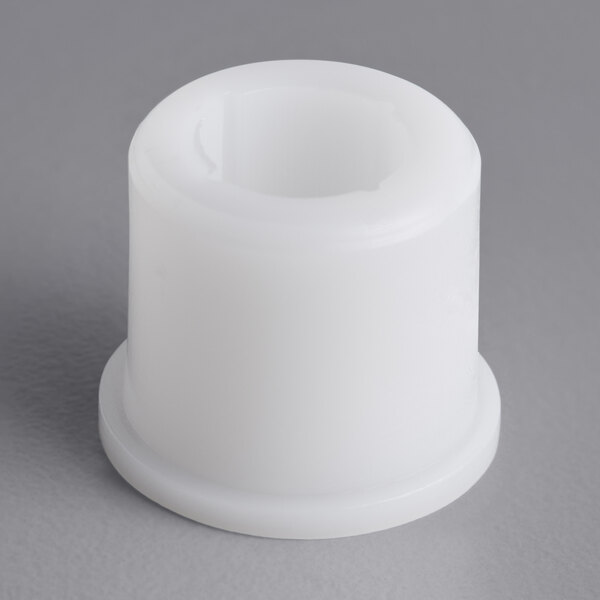 A white plastic Garde bushing with a hole on a gray surface.