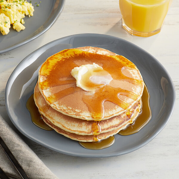 An American Metalcraft Crave melamine plate with a stack of pancakes topped with butter and syrup.