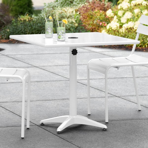 A white Lancaster Table & Seating outdoor table with chairs on a patio.
