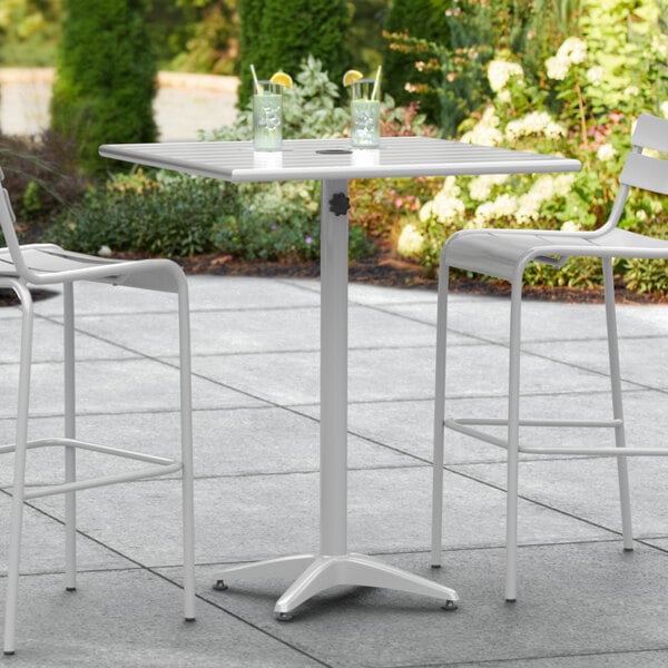 A white table with two chairs and a bar stool on a patio.