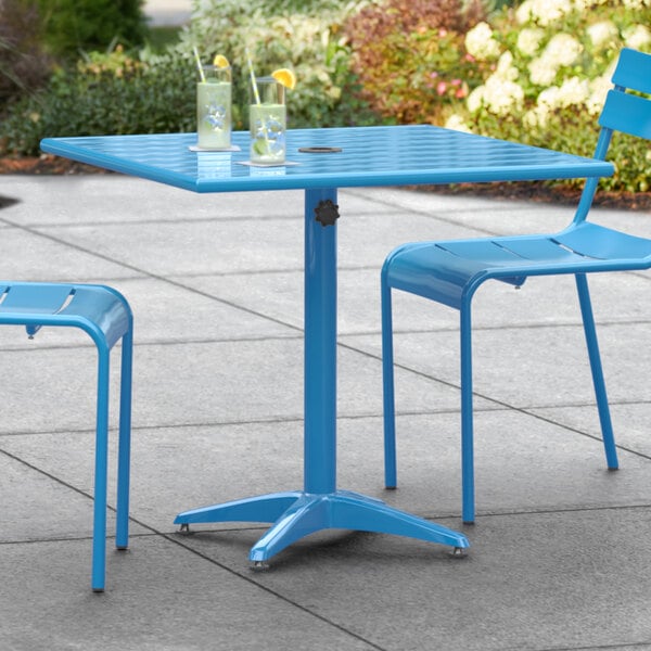 A blue Lancaster Table & Seating outdoor table with chairs on a patio.