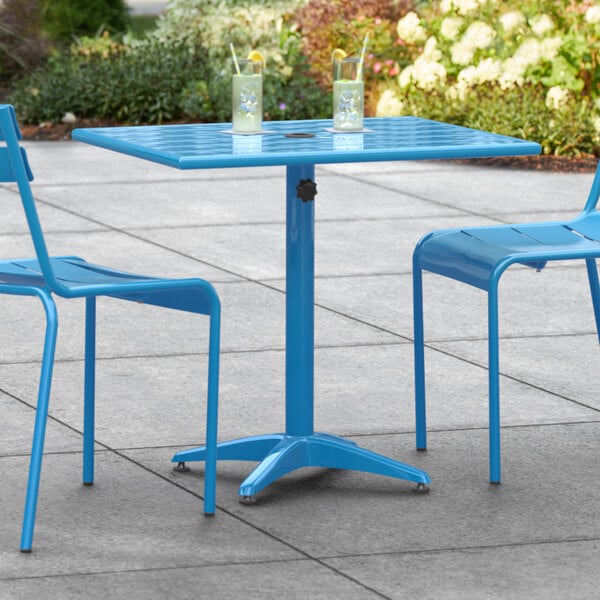 A blue Lancaster Table & Seating outdoor table with two chairs.