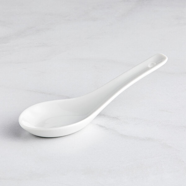 A Bauscher bright white porcelain tasting spoon on a white surface.