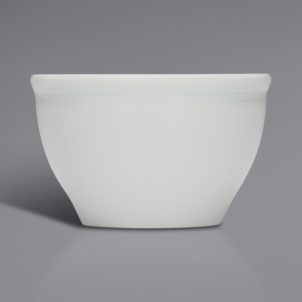 A Bauscher bright white porcelain sugar bowl with a handle on a grey surface.