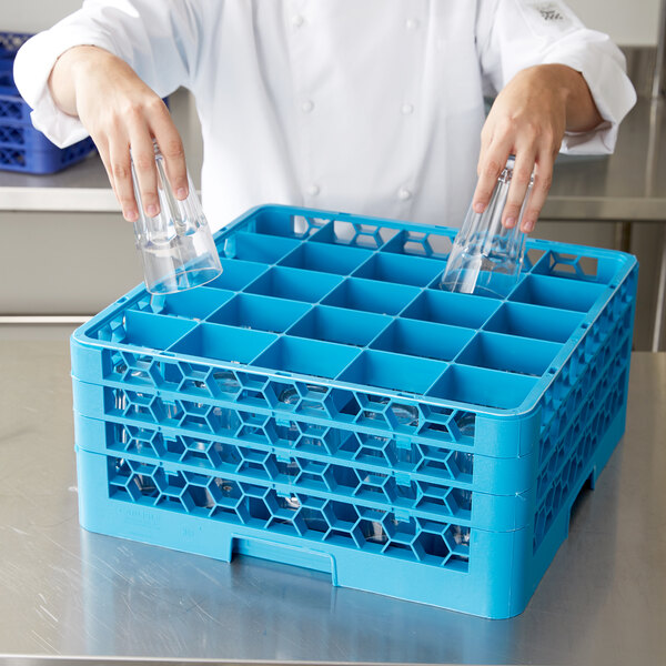 A chef using a Carlisle blue plastic glass rack to hold clear glasses.