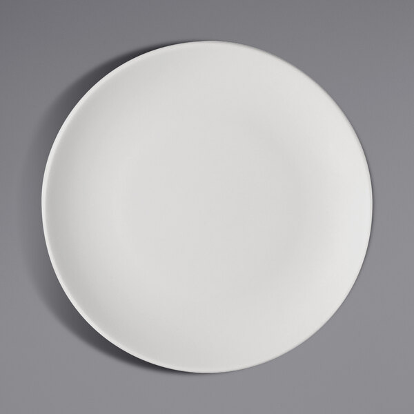 A Bauscher bright white porcelain flat coupe plate on a gray surface.