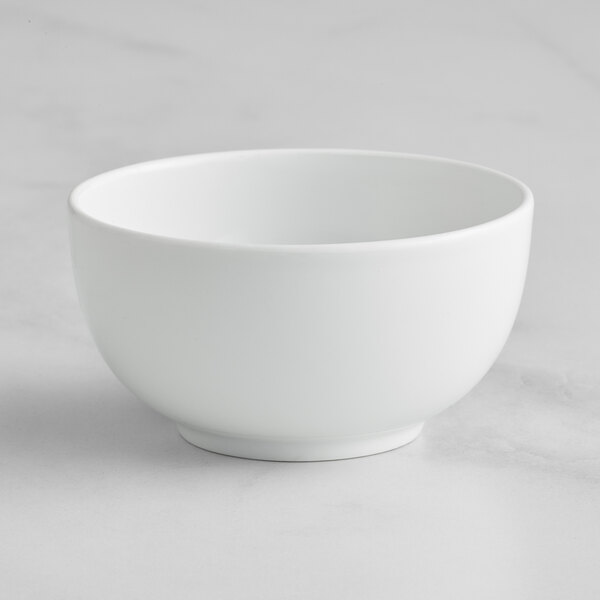 A Bauscher bright white porcelain teacup on a white surface.