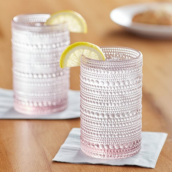 Two Fortessa Jupiter pink beverage glasses with lemon slices on them.