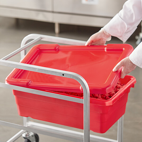 A person in white gloves holding a red Choice lid for a meat lug container.