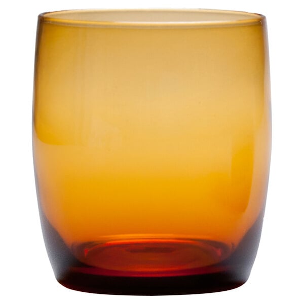 A close up of a Fortessa amber beverage glass with a brown and yellow rim.
