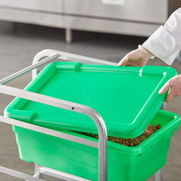 A person in a white lab coat and gloves holding a green Choice meat lug lid.