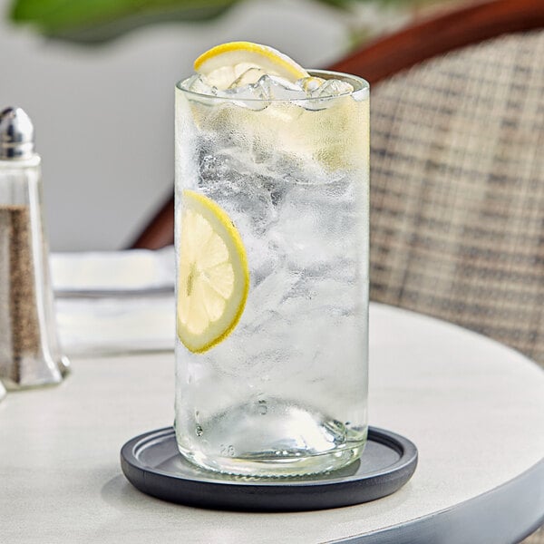 A Fortessa wine tumbler filled with water, ice, and lemon slices on a coaster.