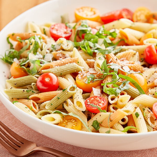 A bowl of Barilla tri-color penne pasta with tomatoes and basil.
