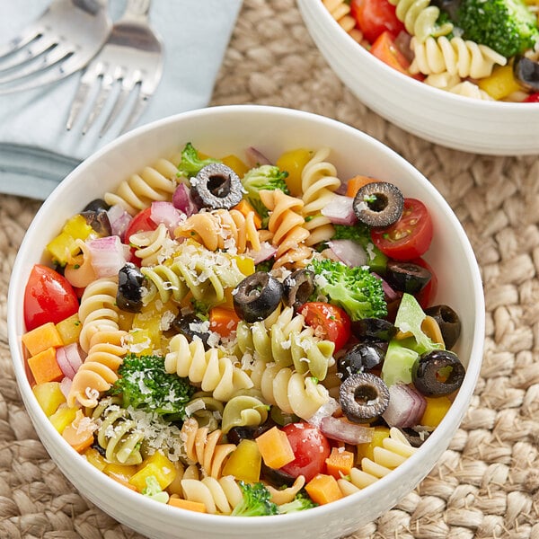 A bowl of tri-color rotini pasta salad with vegetables and olives.
