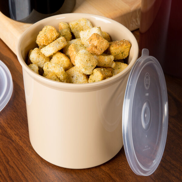A beige Carlisle round plastic crock with a lid filled with croutons.