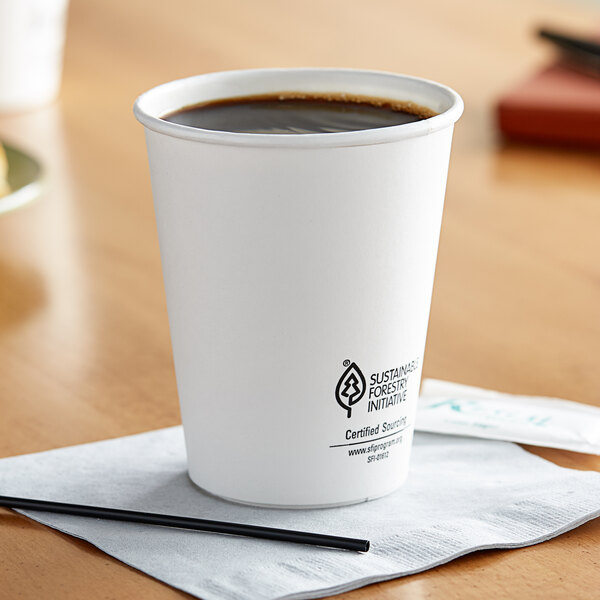 A Dart ThermoGuard white paper hot cup filled with coffee on a table.