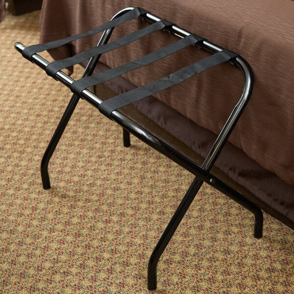 A black Lancaster Table & Seating folding luggage rack with straps on it.