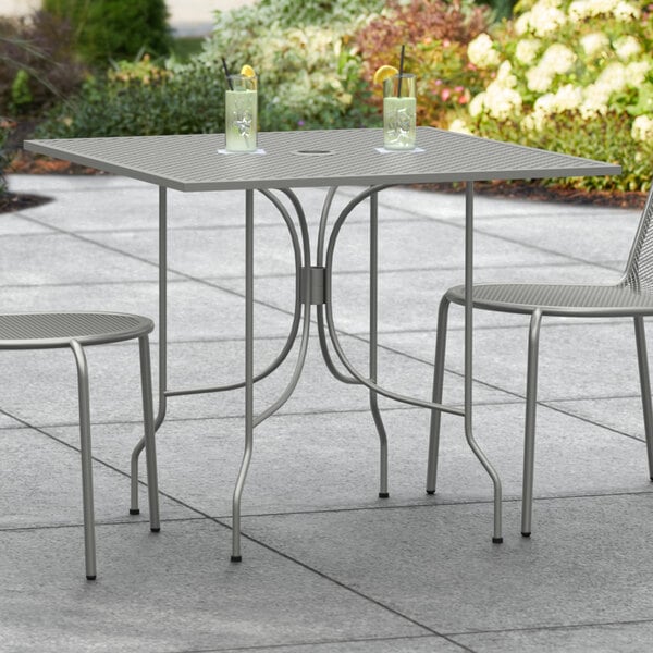 A Lancaster Table & Seating Harbor Gray outdoor table with two chairs on a patio.