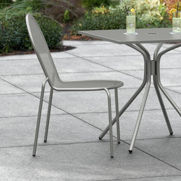 A Lancaster Table & Seating Harbor Gray Outdoor Side Chair on a patio