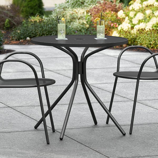 A Lancaster Table & Seating Harbor Black outdoor table with two chairs on a patio.