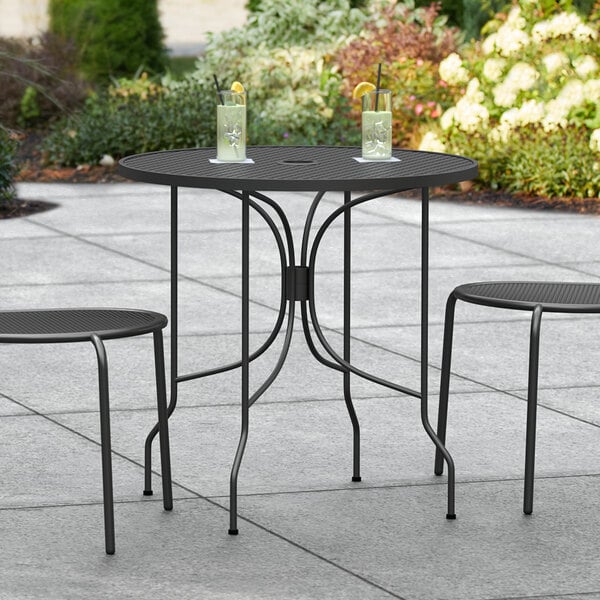 A Lancaster Table & Seating Harbor Black outdoor table with two chairs on it.