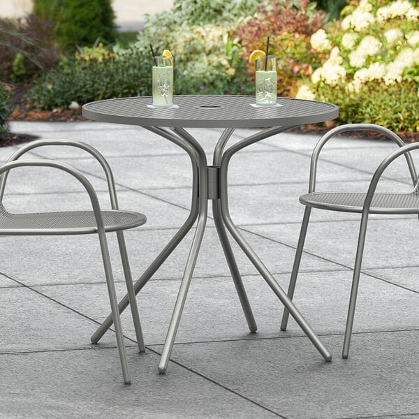 A Lancaster Table & Seating Harbor Gray outdoor table with modern legs on a patio.