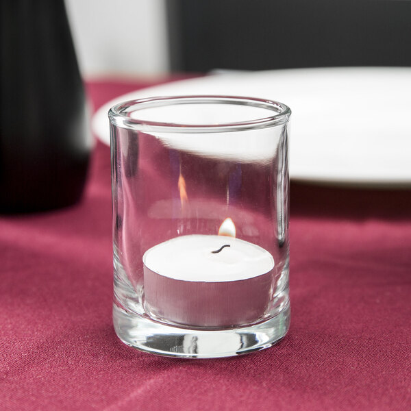 A close up of an Anchor Hocking Concord glass votive holder with a white candle inside.