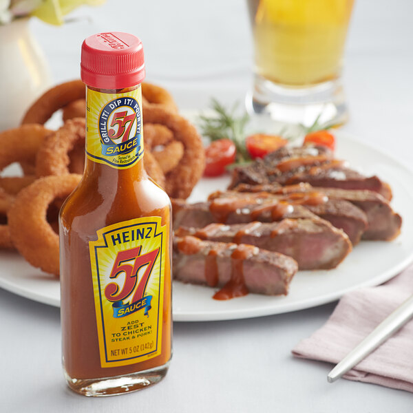 A Heinz 57 Sauce bottle next to a plate of food.
