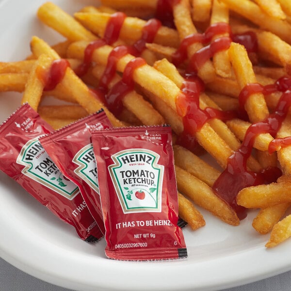A plate of french fries with Heinz ketchup and ketchup packets.
