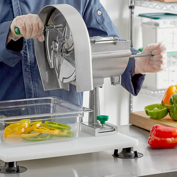 A person using a Garde fruit and vegetable rotary slicer to cut a green bell pepper.