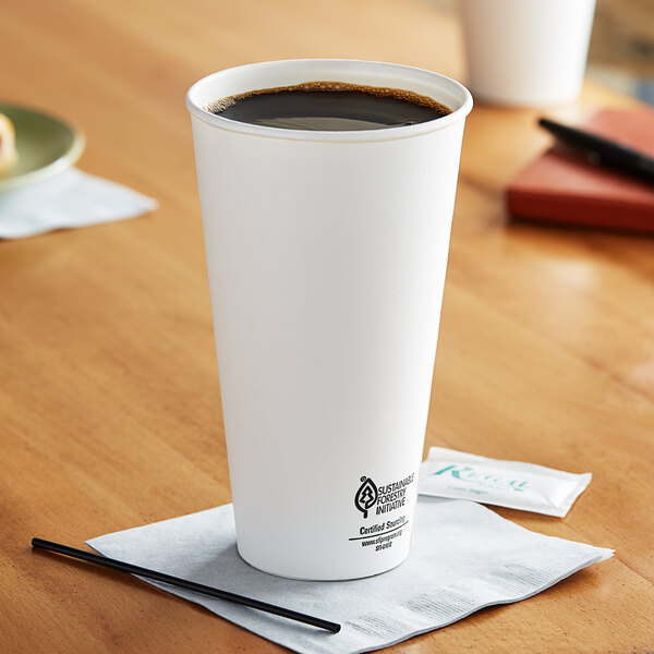 A close-up of a Dart white paper hot cup full of coffee on a table.
