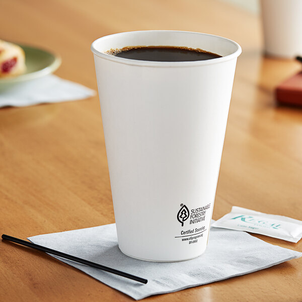 A white Dart ThermoGuard paper hot cup with a lid on a table with a cup of coffee.