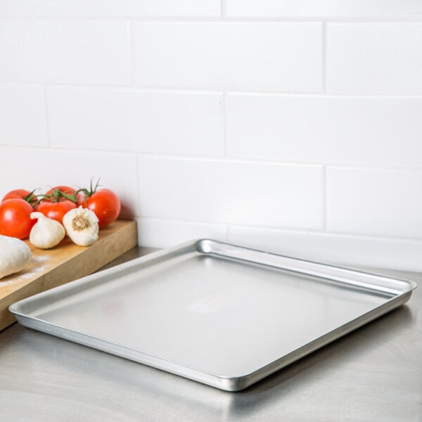 An American Metalcraft square stainless steel deep dish pizza pan with food on it next to a cutting board.