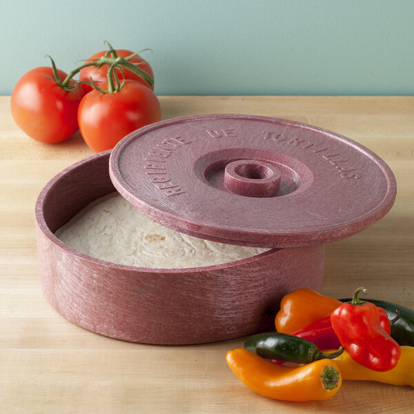 A round red HS Inc. polyethylene tortilla server with a lid open next to a group of peppers.