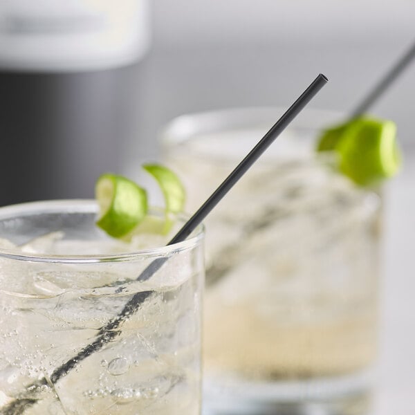 Two glasses of drinks with lime and EcoChoice black compostable PLA cocktail straws.