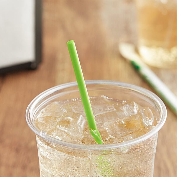 A glass of iced tea with a green EcoChoice PLA straw on a table.