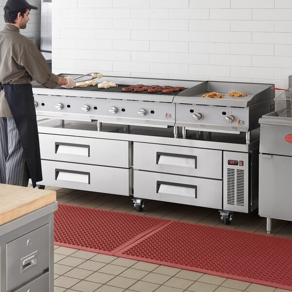 A man cooking on a commercial kitchen refrigerated chef base with a gas radiant charbroiler and griddle.