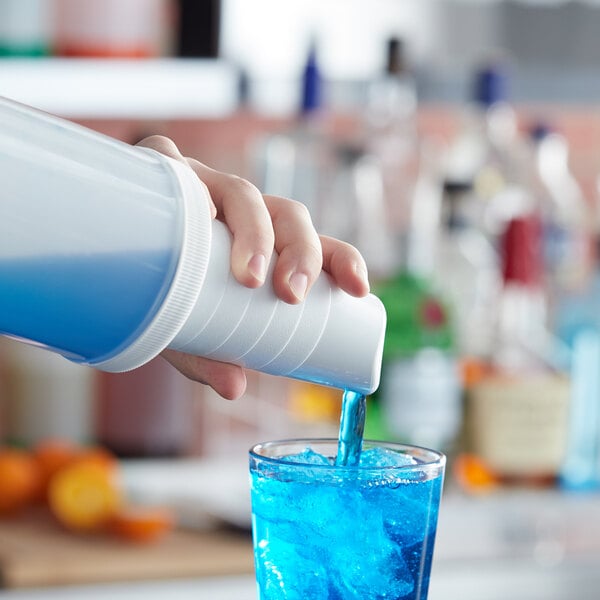 A person using a Tablecraft PourMaster white spout to pour blue liquid into a glass.