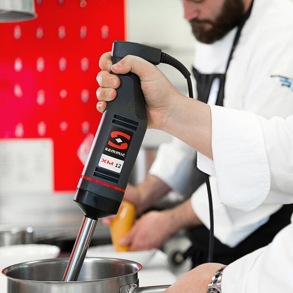 A chef using a Sammic XM-12 immersion blender in a metal bowl.