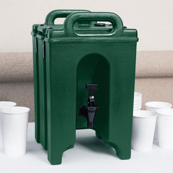 A green plastic Cambro insulated beverage dispenser with a black spigot and white cups.