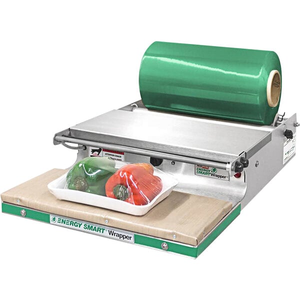 A Bizerba countertop wrapping machine with a green roll of plastic wrapping, sealing a red pepper.