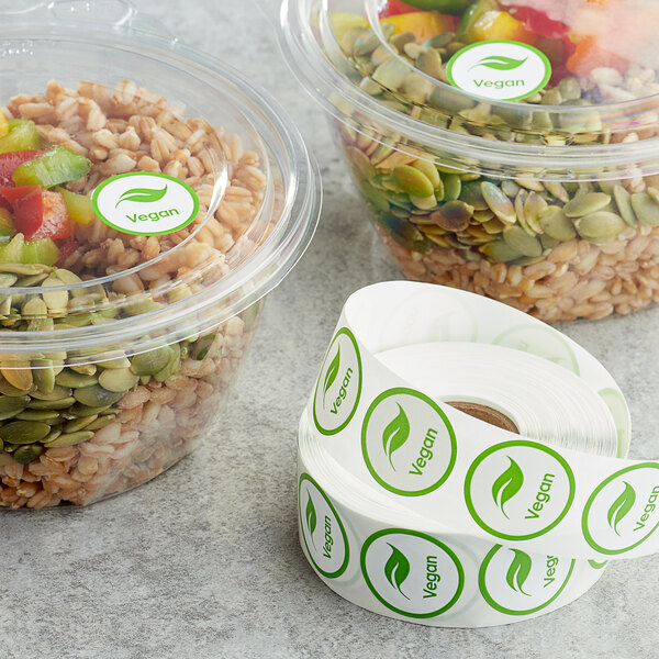 A Point Plus roll of green vegan food labeling stickers on a table with containers of food.